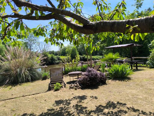 Détente absolue Jardin verdoyant avec chaises, table et arbres sous un ciel bleu.