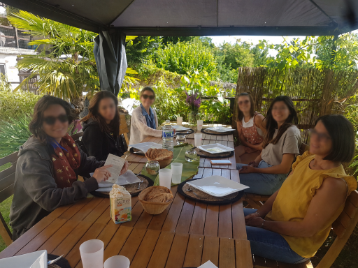 Repas convivial Un groupe de six personnes assises autour d'une table à l'extérieur, en pleine nature.