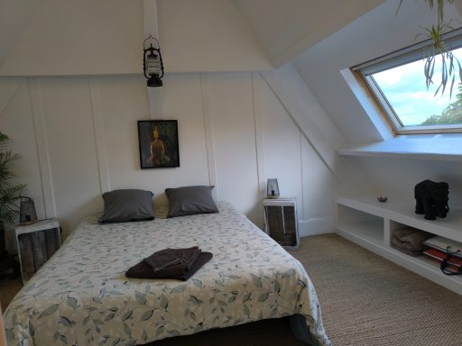 Chambre à l’étage avec vue rivière Chambre lumineuse avec un lit, des oreillers, une étagère et une fenêtre sur le jardin.